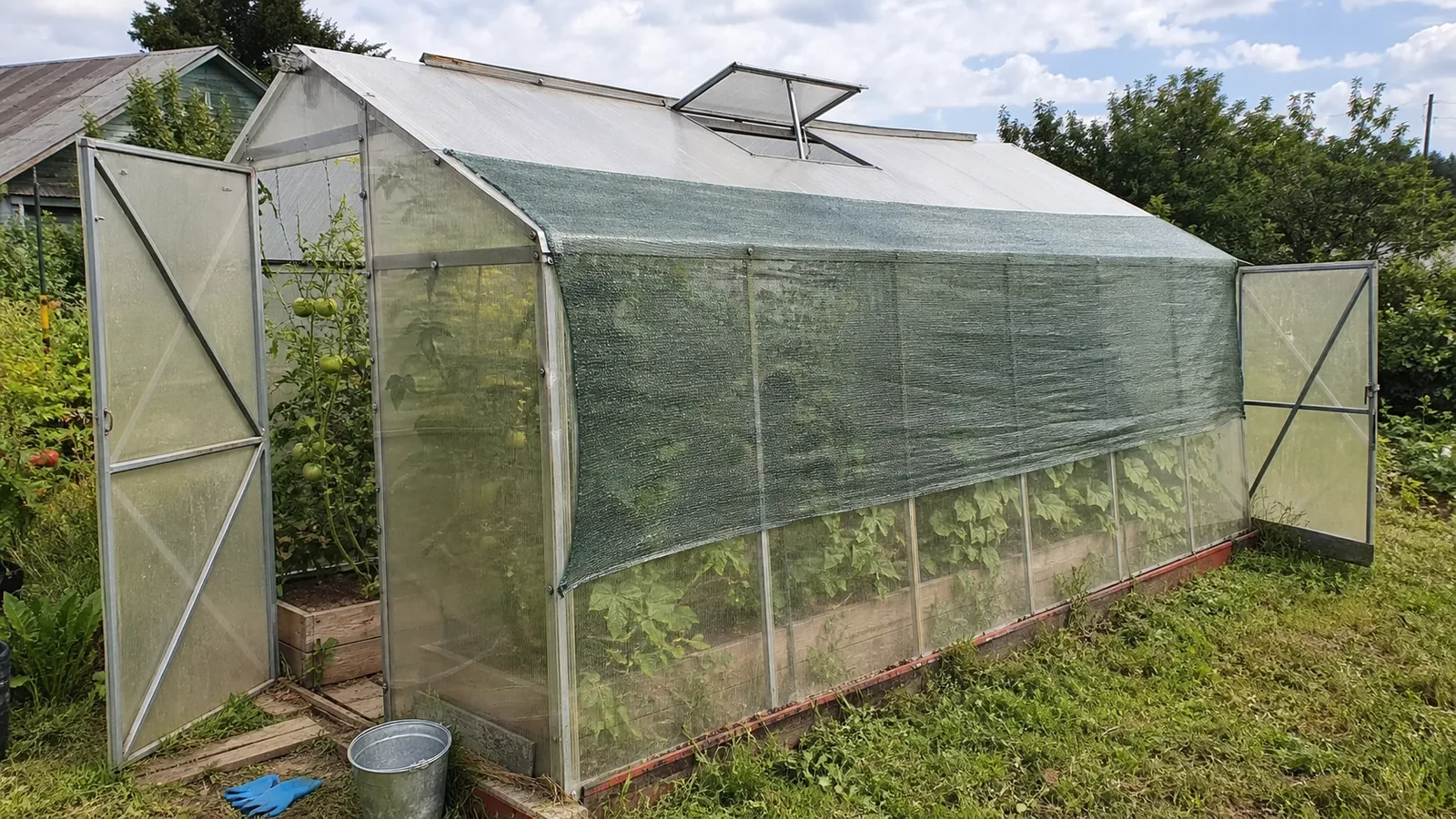 Теплица с внешним притенением и открытыми дверями в жаркий день